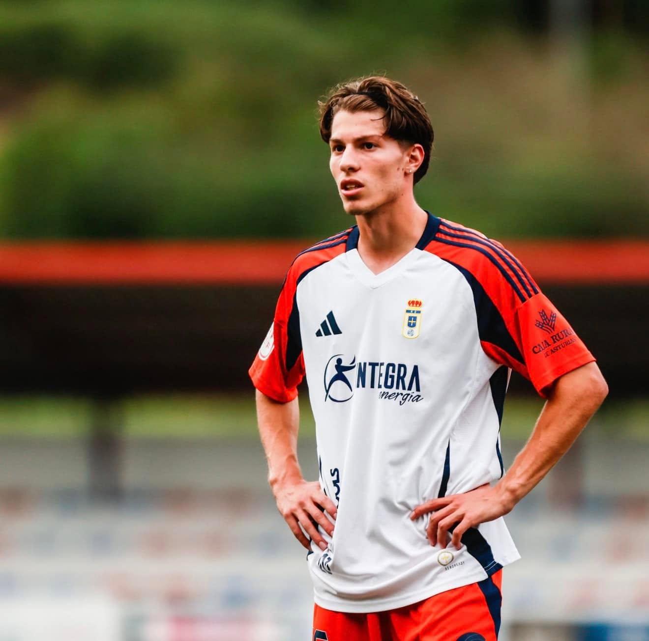 Football player on the pitch wearing a white and orange kit